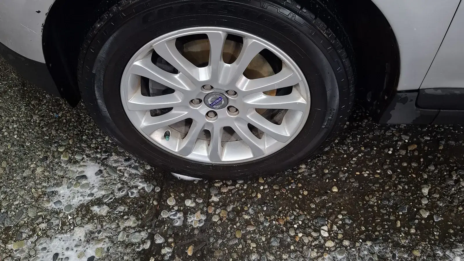 Freshly hand-washed wheel and tire at Derek's Auto Detail in Seattle, wash foam still on the floor