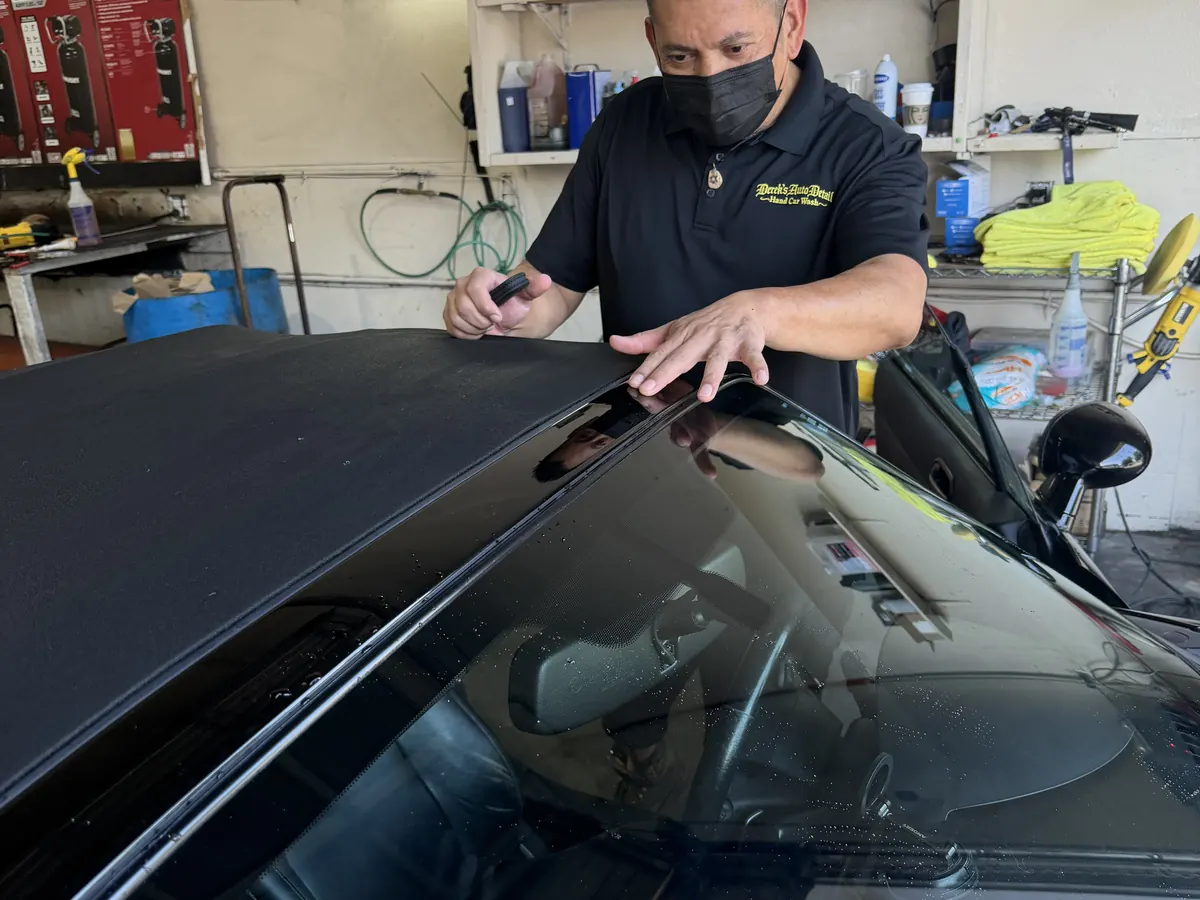 A Derek's Auto Detail technician working on a car by hand inside the Seattle shop