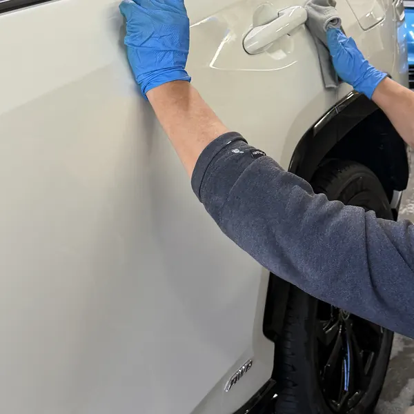 Hand washing a white SUV door with a microfiber mitt