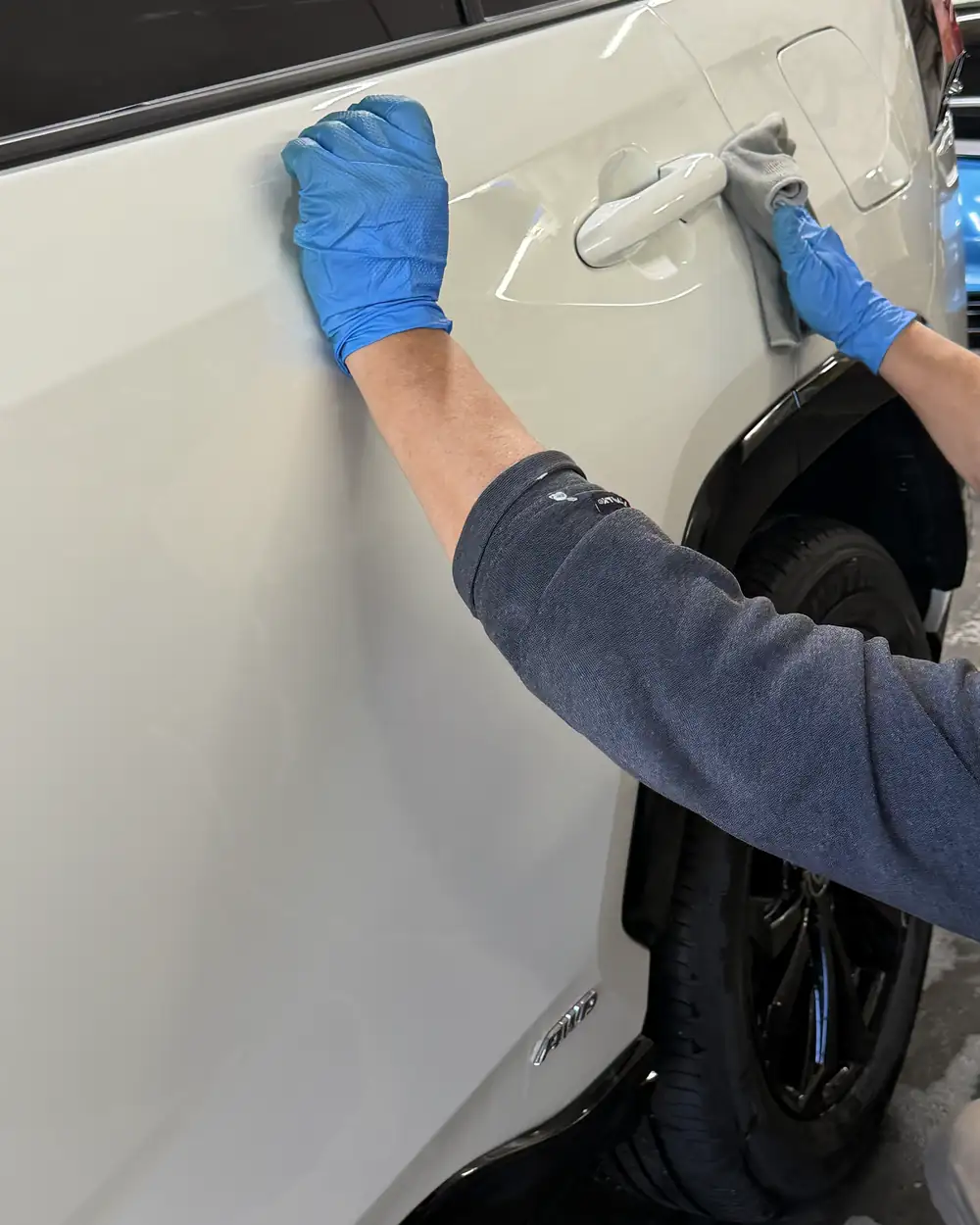 Hand-drying a white car door and handle with a microfiber towel at Derek's Auto Detail in Seattle